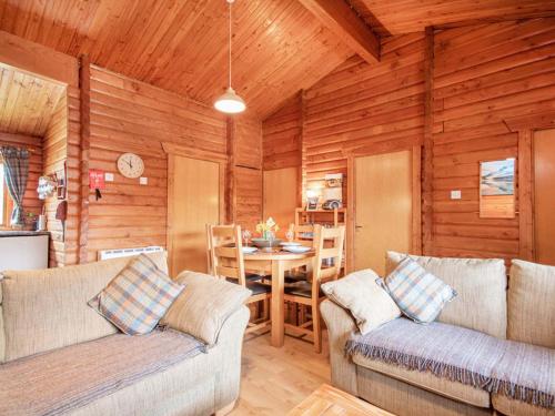 a living room with two couches and a table at Lochside Log Cabin in Brora