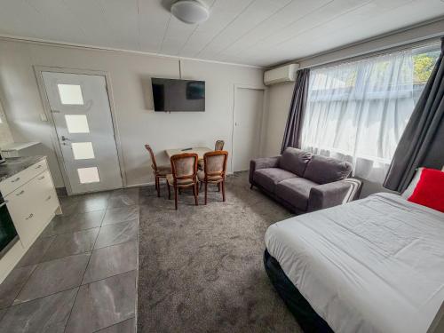 a bedroom with a bed and a couch and a table at Avana Suites in Lower Hutt
