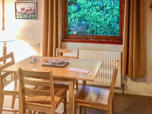 a wooden table and chairs in a room with a window at Achnacarry Cottage in Evelix