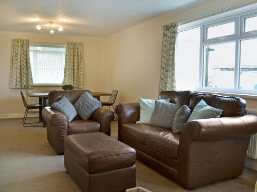 a living room with two leather chairs and a table at La Falda in Sutton on Sea