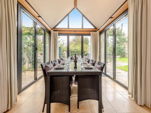 a dining room with a table and chairs and windows at New Inn Farmhouse in Marnhull