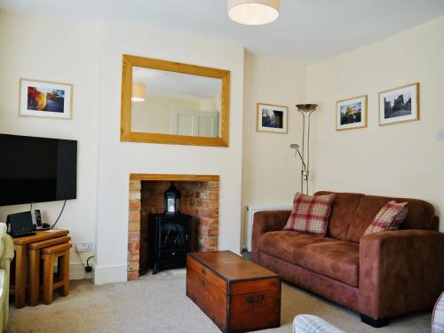 a living room with a couch and a fireplace at Wells Cottage in Hook Norton