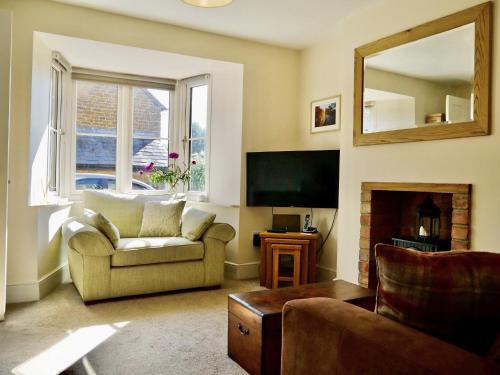 a living room with a couch and a television at Wells Cottage in Hook Norton