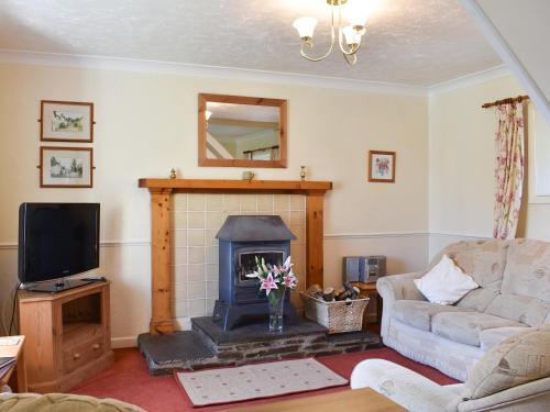 a living room with a fireplace and a tv at Hayloft - Ukc4241 in Lanreath