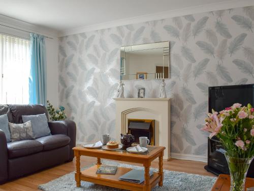 a living room with a fireplace and a mirror at The Marches in Anstruther