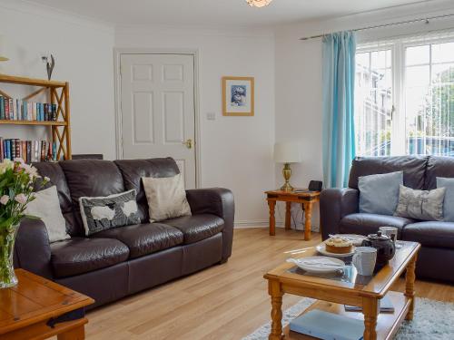 a living room with two leather couches and a coffee table at The Marches in Anstruther