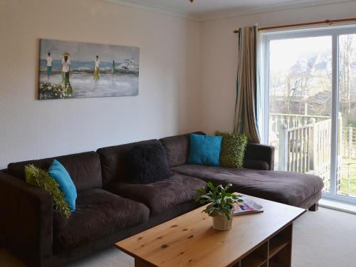 a living room with a brown couch and a table at Willow Cottage in Warkworth