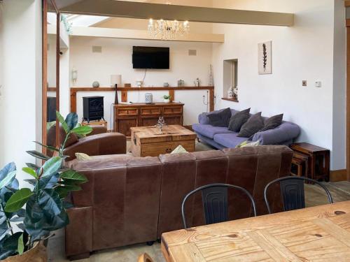 a living room with two couches and a tv at Hobland Barn in Paston