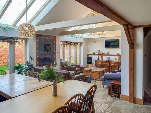 a conservatory with a table and a living room at Hobland Barn in Paston