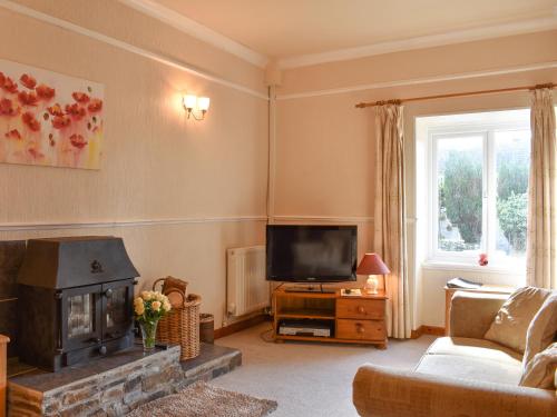 a living room with a fireplace and a television at Linhay - Ukc4242 in Lanreath