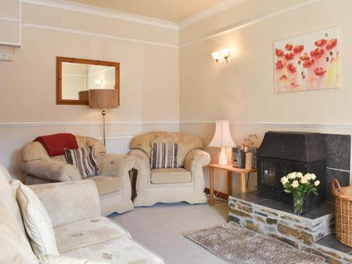 a living room with two chairs and a fireplace at Linhay - Ukc4242 in Lanreath