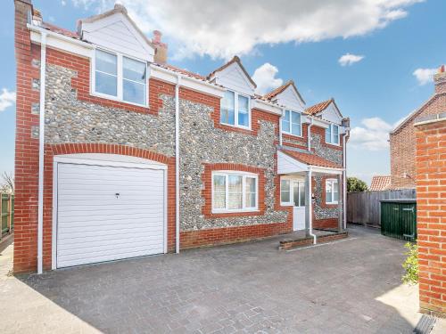 a brick house with a white garage at Sandbanks in Bacton