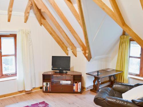 a living room with a couch and a tv on a table at Walnut Tree Cottage in Burbage