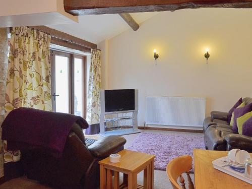 a living room with a couch and a tv at Elm Tree Cottage in Kirkbymoorside