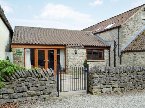 a stone house with a gate and a stone wall at Elm Tree Cottage in Kirkbymoorside