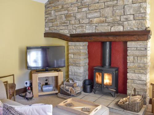 a living room with a fireplace and a tv at Timbessie Barn in Carperby