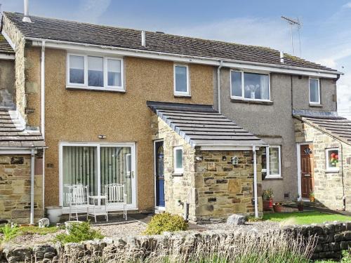 a brick house with a porch and a bench at Bank View in Settle