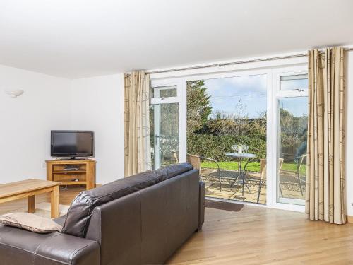 a living room with a couch and a sliding glass door at 5 Red Rock Apartments in Dawlish Warren