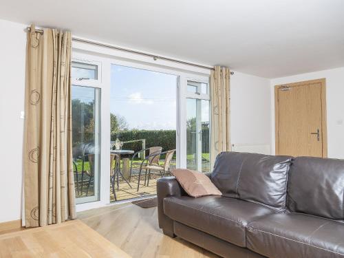 a living room with a leather couch and a balcony at 4 Red Rock Apartments in Dawlish Warren