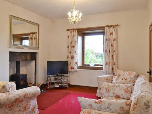 a living room with two chairs and a television at Old Post Office House in Knockbain