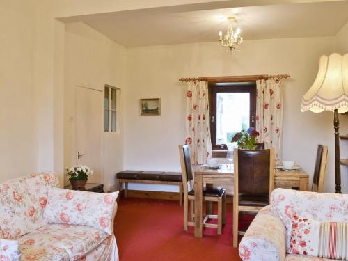 a living room with a table and a dining room at Old Post Office House in Knockbain