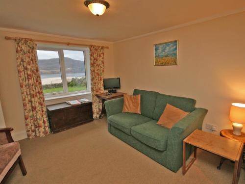 a living room with a green couch and a window at Melness Cottage in Melness