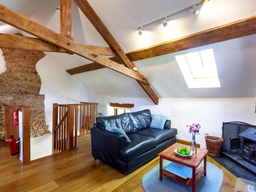 a living room with a black leather couch and a table at Cider Barn in Chulmleigh