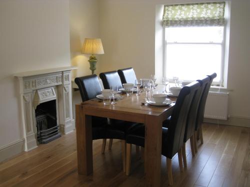 a dining room with a table with chairs and a fireplace at Swallow's Nest in Bradwell