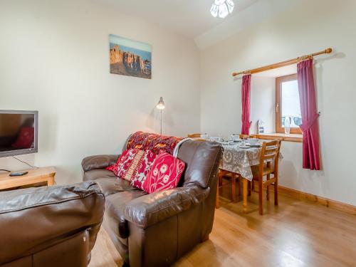 a living room with a leather couch and a table at The Byre Mey in Scarfskerry