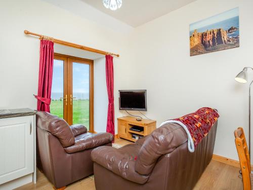 a living room with two leather chairs and a television at The Byre Mey in Scarfskerry