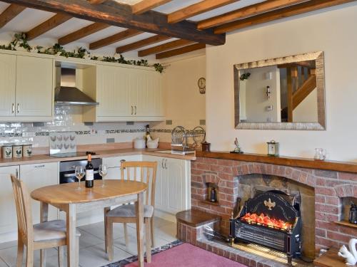 a kitchen with a fireplace and a table and a dining room at Farmhouse Cottage in North Rode