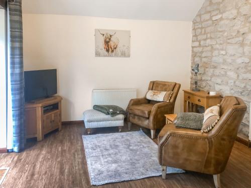 a living room with two chairs and a television at Plum Tree Cottage in Kirkbymoorside
