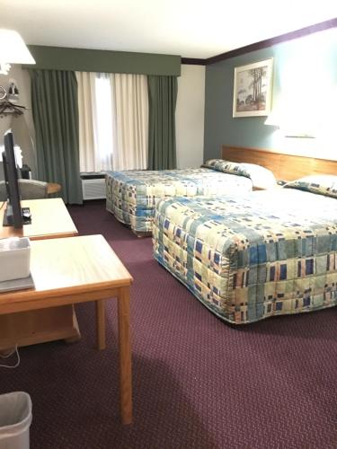 a hotel room with two beds and a desk at Becker inn & Suites in Becker
