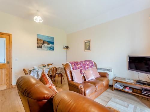 a living room with a leather couch and a table at The Barn Mey in Scarfskerry