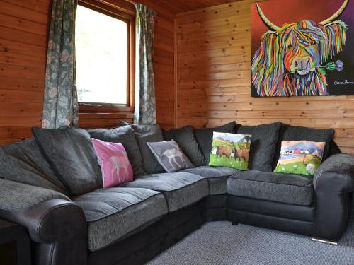 a couch in a room with a cow painting on the wall at Loch Arkaig in Banavie