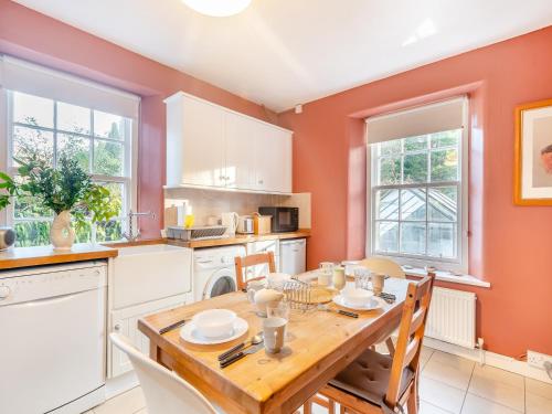 a kitchen with a wooden table and a dining room at Rhoda's Cottage in Strachur