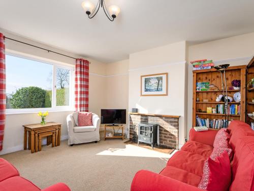 a living room with a red couch and a fireplace at Cartref in Llysfaen