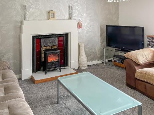 a living room with a fireplace and a tv at Ivydene Cottage in Cromarty