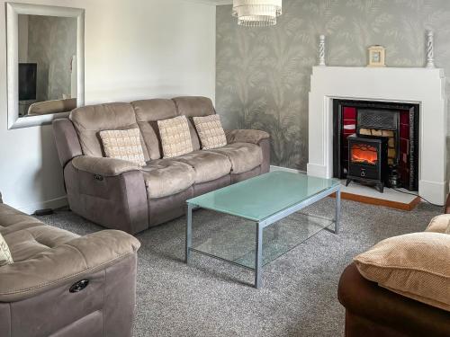 a living room with a couch and a table and a fireplace at Ivydene Cottage in Cromarty