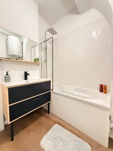 a bathroom with a sink and a bath tub at Le Nid Laonnois Apartment in Laon