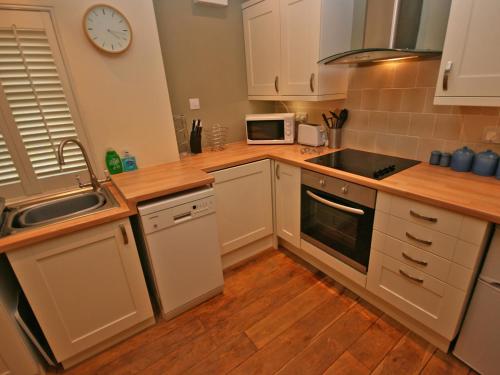 a kitchen with white cabinets and a clock on the wall at Glenfruin Lodge in Helensburgh