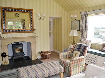 a living room with a fireplace and a couch and chair at Reid's Cottage in Lairg