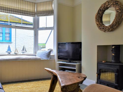 a living room with a tv and a window at Sea Star Cottage in Fowey