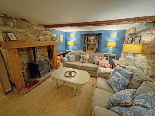 a living room with a couch and a stone fireplace at Windy Nook in Pooley Bridge