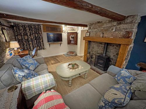 a living room with a couch and a stone fireplace at Windy Nook in Pooley Bridge