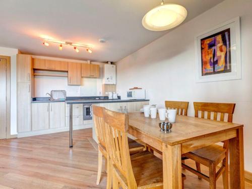 a kitchen with a wooden dining table and chairs at 14 Red Rock Apartments in Dawlish Warren