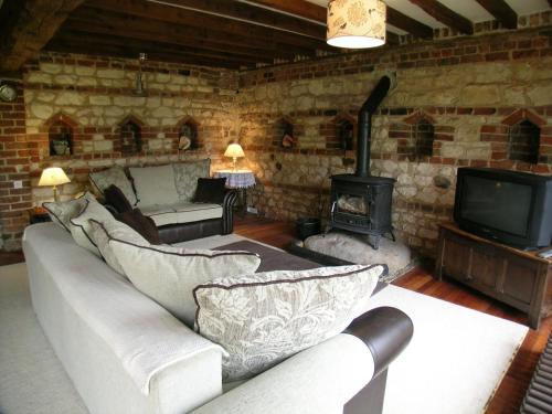 a living room with a couch and a fireplace at Spring Farm Barn in Grindale