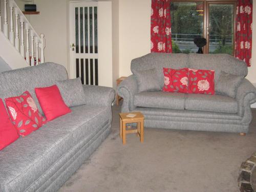 a living room with two couches and a table at Springer Cottage in Llanstephan