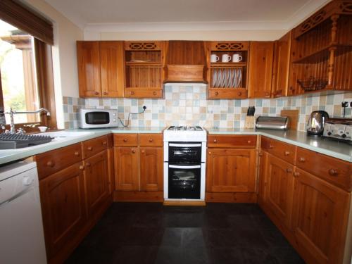 a kitchen with wooden cabinets and a stove top oven at Springer Cottage in Llanstephan