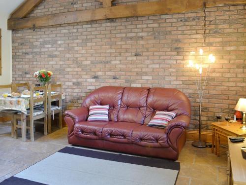 a brown leather couch sitting in a room with a brick wall at Padgett Lodge - 23052 in Folkton